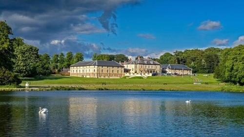 a large building next to a lake with swans in the water at Hardwick Haven, Sedgefield - Near Hardwick Hall in Stockton-on-Tees
