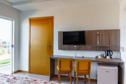 a kitchen with a table and two yellow chairs at Oásis Cabo Frio Hotel in Cabo Frio