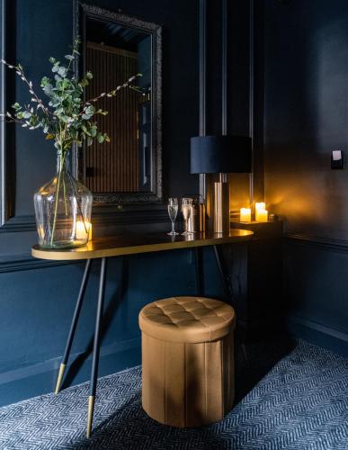 a table with a vase of flowers and a stool at Impossible Motel in York