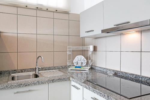 Una cocina con gabinetes blancos y un fregadero. en Casa Médano 3 By Médano Rentals, en El Médano