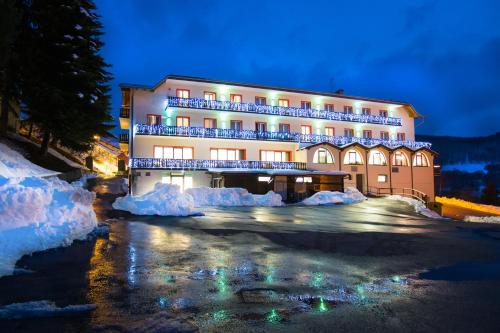 un grand bâtiment avec de la neige autour de lui la nuit dans l'établissement Hotel Polsa, à Brentonico