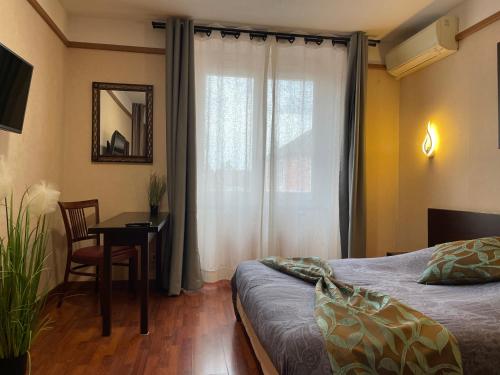 a bedroom with a bed and a desk and a window at L'EMBLEME - BOUTIQUE HOTEL in Beaurepaire