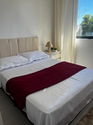 uma cama grande num quarto com uma janela em Lindo apartamento em Curitiba