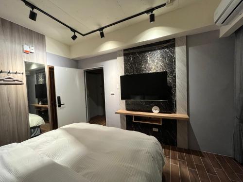 1 dormitorio con 1 cama y TV de pantalla plana en 飛鳥集行館 en Hu-hsia