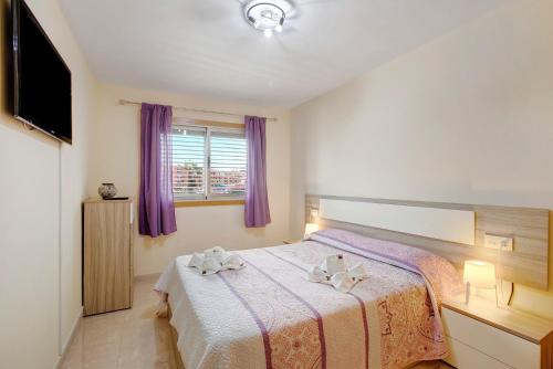 1 dormitorio con 1 cama grande y cortinas moradas en La Perla D14 en el Médano, en El Médano