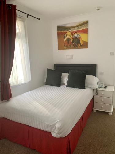 a bedroom with a large white bed with a window at Sarum Apart-Hotel in Saint Helier Jersey