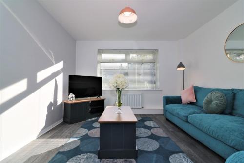 a living room with a blue couch and a tv at Signature - Morland House in East Kilbride