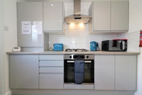 kuchnia z białymi szafkami i kuchenką z krawatem w obiekcie Signature - Sydney House w mieście East Kilbride