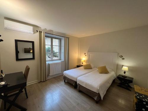 a bedroom with a bed and a desk and a window at Hotel-Restaurant Saint Romain Logis in Anse