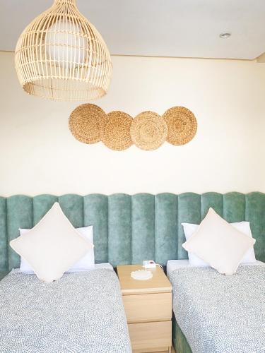 a bedroom with two beds and a green tufted headboard at Appartement Cosy, vue sur mer in Mohammedia