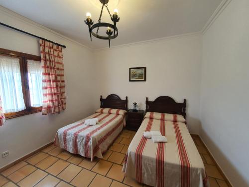 1 dormitorio con 2 camas y lámpara de araña en Hotel-Restaurante Venta Tomas, en Almuradiel