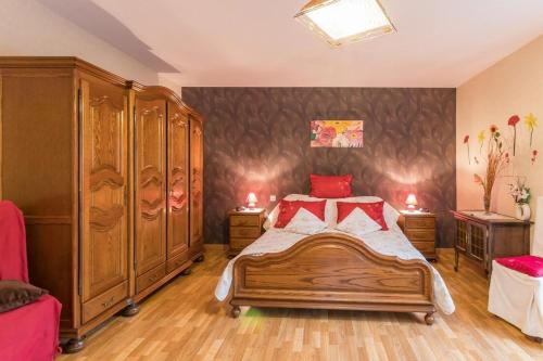 Schlafzimmer mit einem Holzbett mit roten Kissen in der Unterkunft Le clair-soleil in Briaucourt
