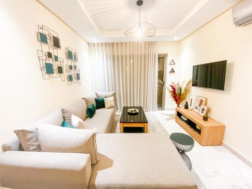 sala de estar con sofá y TV en Appartement Cosy, vue sur mer, en Mohammedia