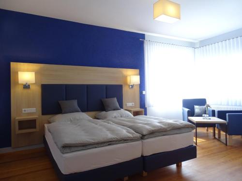a bedroom with a large bed with a blue wall at Gästehaus Schattemorellsche in Fürfeld