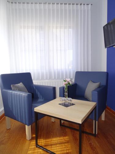a living room with two blue chairs and a table at Gästehaus Schattemorellsche in Fürfeld
