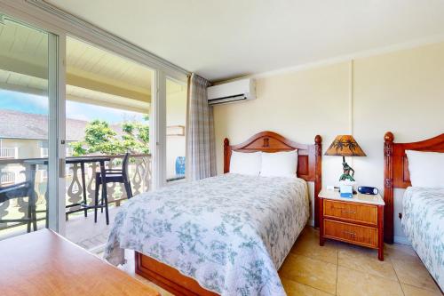 a bedroom with a bed and a balcony at Islander on the Beach 315 in Kapaa