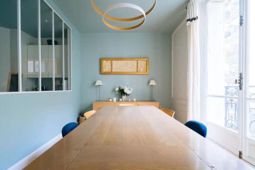 un grande tavolo in legno in una stanza con pareti blu e una grande finestra di Spacious Parisian Family Apartment In 7th a Parigi