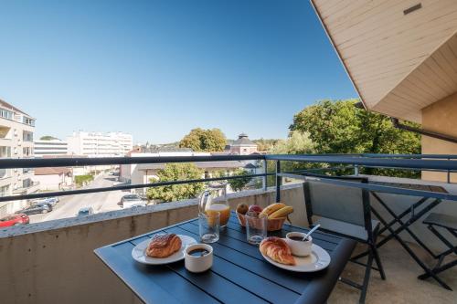 une table avec deux assiettes de nourriture sur un balcon dans l'établissement Residence Des Thermes, à Lons-le-Saunier