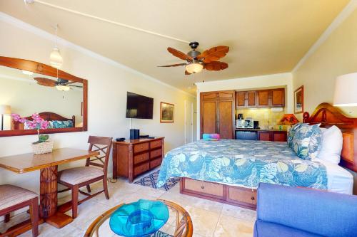 a bedroom with a bed and a table and a kitchen at Islander on the Beach 142 in Kapaa