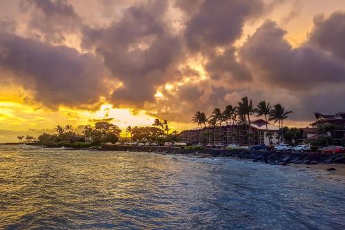a sunset over a beach with palm trees and buildings at Islander on the Beach 101 in Kapaa