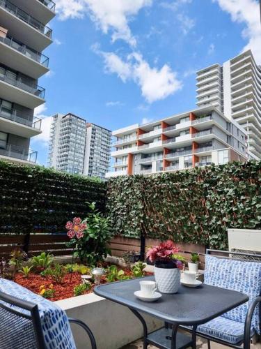 a patio with a table and chairs and buildings at Garden View of Macquarie Park Paradise in Sydney