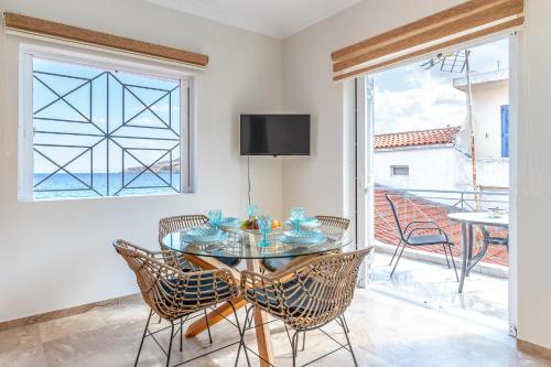 uma sala de jantar com uma mesa e cadeiras de vidro e uma janela em Pallas em Keratea