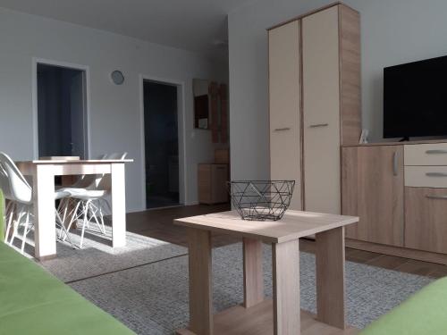 a living room with a table and a tv at Apartments Manna Palic in Palić