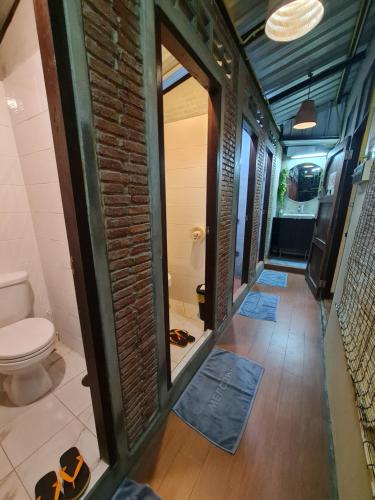 uma casa de banho com um WC e uma parede de tijolos em Non House Hostel บ้านนอนโฮสเทล em Bangkok