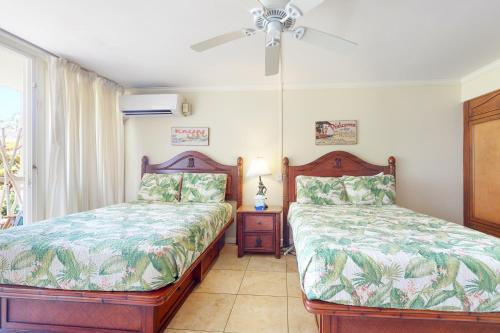 1 dormitorio con 2 camas y ventilador de techo en Islander on the Beach 111 en Kapaa