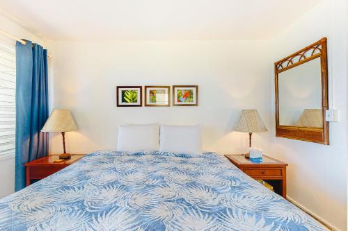 a bedroom with a bed and two lamps and a mirror at Kapa'a Sands 14 in Kapaa