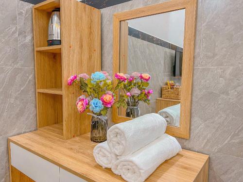 a bathroom with a mirror and towels and flowers at Homestay Qhome in Con Dao