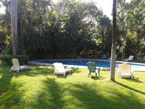 a group of chairs sitting in the grass near a pool at Samara Beach Hotel in Sámara