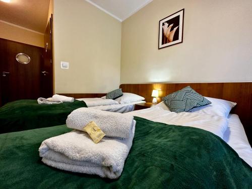 a hotel room with three beds with towels on them at Rezydencja Korab in Międzyzdroje