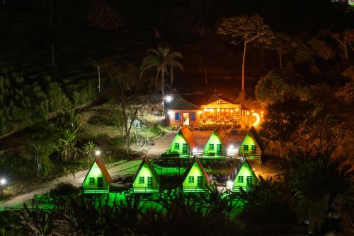 une maison éclairée la nuit avec des lumières vertes dans l'établissement Pousada Recanto da Lua, à Caparaó Velho