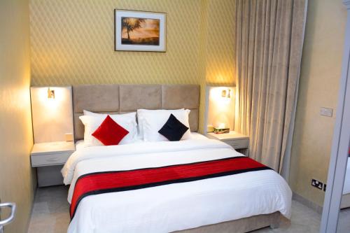 a bedroom with a large bed with red and black pillows at ذا فيفتى ايت السالمية in Kuwait