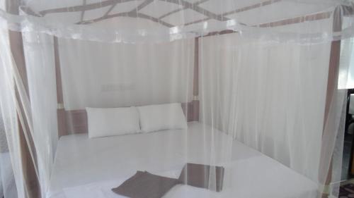 a small room with a bed with white curtains at Mirissa Cocoon in Mirissa
