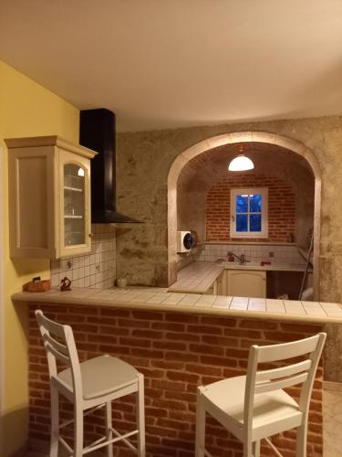 eine Küche mit 2 Stühlen und einer Ziegelwand in der Unterkunft Maison dans un petit Mas en pleine campagne in Saint-Jean-de Laurs