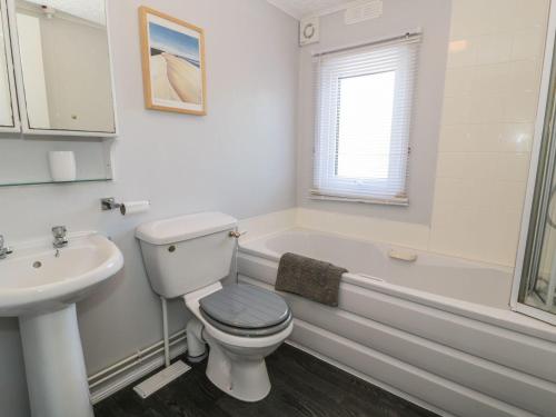 a bathroom with a toilet and a tub and a sink at Orchard Lodge in Pwllheli