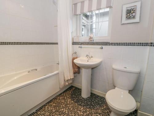 La salle de bains est pourvue de toilettes, d'un lavabo et d'une baignoire. dans l'établissement The Orchard, à Pwllheli
