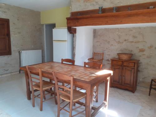 cocina con mesa de madera con sillas y nevera en Maison dans un petit Mas en pleine campagne, en Saint-Jean-de Laurs