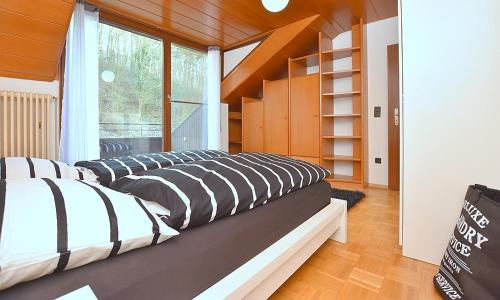 a room with three beds and a large window at BB City Appartements in Böblingen
