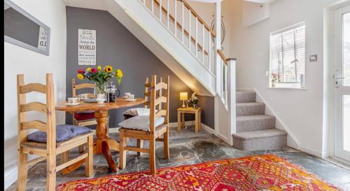 uma sala de jantar com mesa, cadeiras e escadas em Cottage in Worcestershire em Evesham