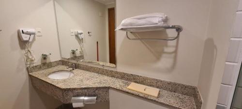 a bathroom counter with a sink and a mirror at Flat Live & Lodge c/ vaga de garagem UH1003 in Sao Paulo