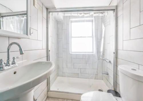 Baño blanco con bañera y lavamanos en Beautiful 3BR 1BA Apartment in Kips Bay, en Nueva York