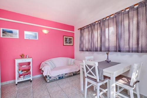 Schlafzimmer mit rosa Wänden, einem Tisch und Stühlen in der Unterkunft House Mali Losinj (137) in Mali Lošinj