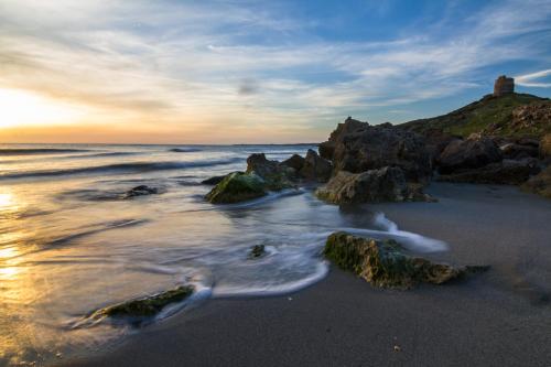 a beach with rocks and the ocean at sunset at West Sardinia Apartments in Càbras