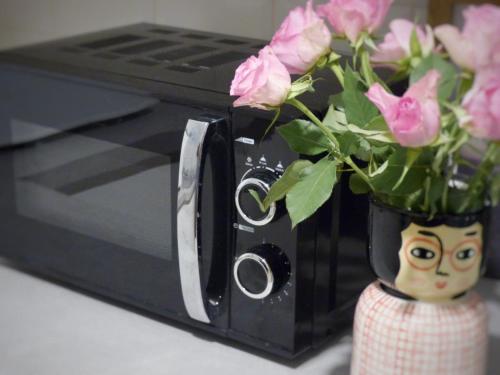 a vase of pink roses in front of a microwave at Poppy's Place in Oakworth