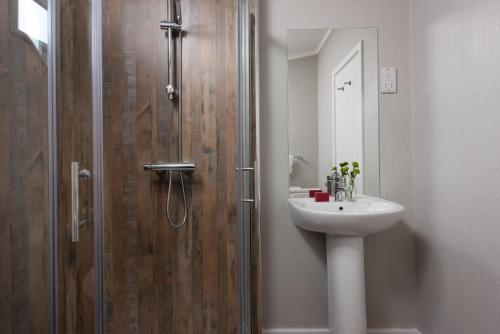 een badkamer met een douche en een wastafel bij Daisy Lodge, 6 Roadford Lake Lodges in Lifton