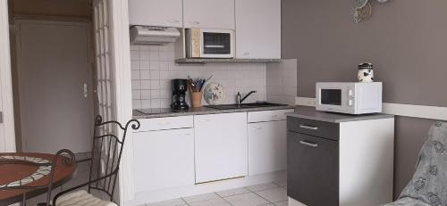 une petite cuisine avec des armoires blanches et un micro-ondes dans l'établissement L'Opale, à Berck-sur-Mer