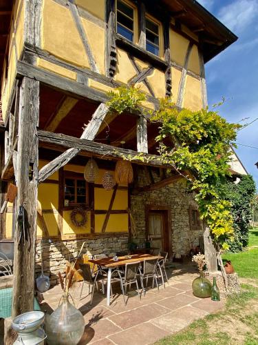 a house with a table and chairs in front of it at Gîte Le Chut - Piscine & Jacuzzi - 11 à 14 personnes in Rangen